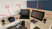 A V R workstation has a 360 V R headset, two V R sensors, a computer, an additional screen, and V R controller grips.