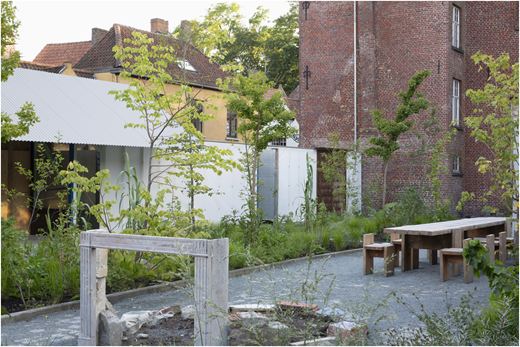 A community garden with a pavilion and wooden furniture in Bruges, Belgium.