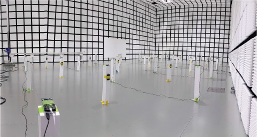 An image shows the interior of a large anechoic chamber or similar testing environment, with white walls and ceiling covered in black tape forming a large grid pattern.