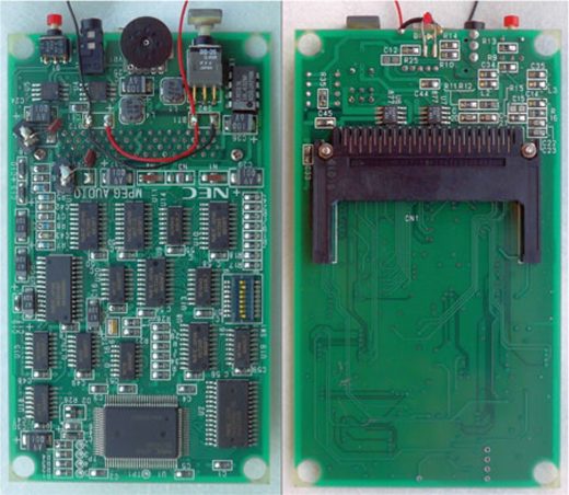 A photograph showing two printed circuit boards, one populated with chips and a buzzer and the other mostly empty with a card connector.