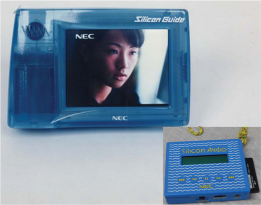 A photograph showing an N E C Silicon Audio player displaying a person on screen and a separate blue remote control unit.