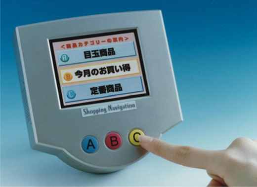 A handheld device with a screen showing menu options while a finger presses the C button below the display.