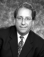 A profile box with a portrait showing an obscured face and text listing John G. Flores s name, job title, organization, office address, telephone number, and email.