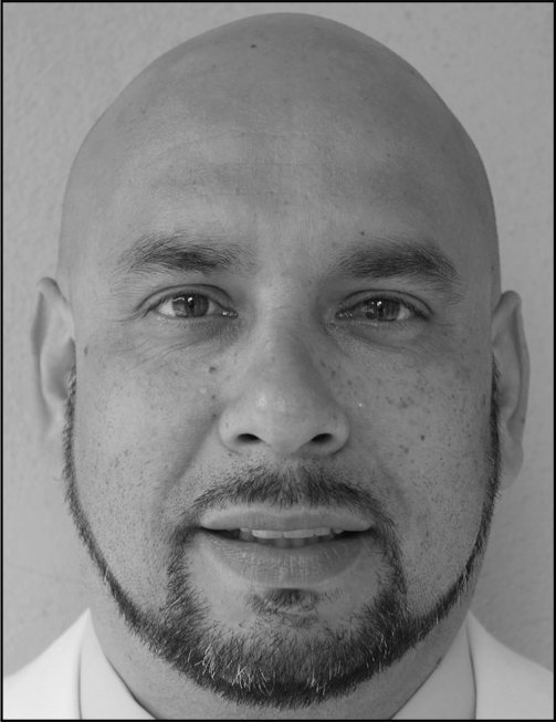 A portrait that presents a man with a shaved head and trimmed beard shown above printed academic and contact information.