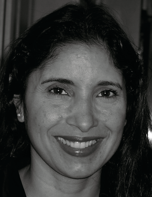 Smiling woman with long dark hair in a black and white close-up portrait. She conveys warmth and friendliness, creating a welcoming and positive tone.