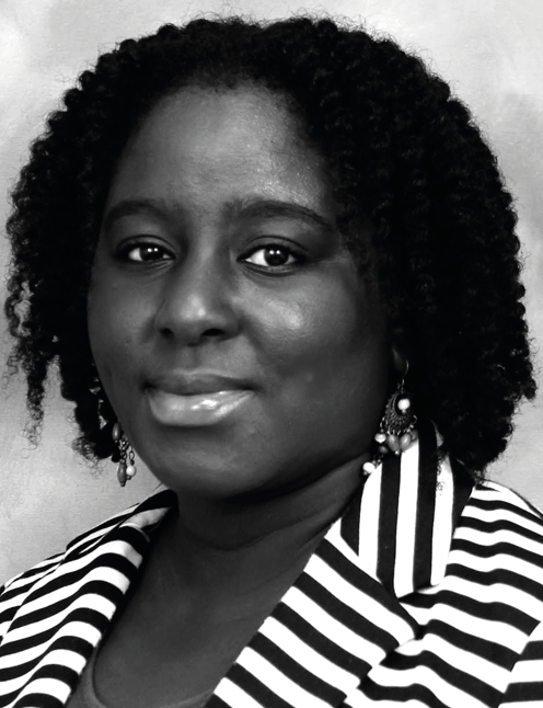 Woman with curly hair and a striped jacket looks forward. .Labelled, Roxanne Hinds, HEART Trust/NTA.