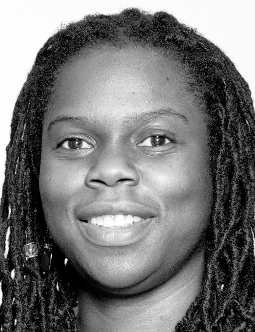 Smiling woman with long dreadlocks poses against a plain background. Labelled, Charlene Desir, Associate Professor, Abraham S. Fischler College of Education.