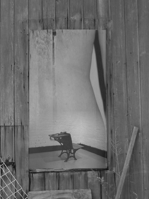 A grayscale illustration showing a boardedup wooden wall with a rectangular opening that reveals a small ornate chair in a room and a partial view of a human torso.
