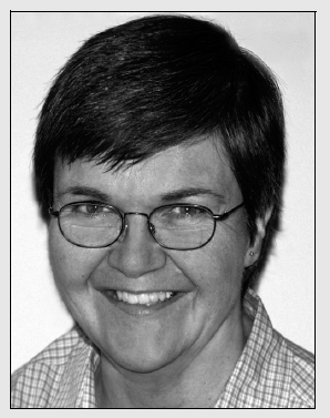 Monochrome portrait of a woman with glasses, gazing into the distance with a pensive look.