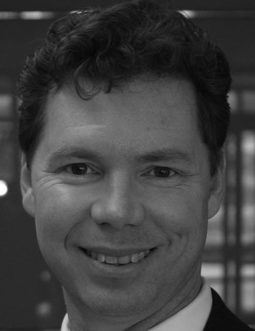 A grayscale portrait of a man above printed text listing his name, job title, company affiliation, mailing address, telephone number, and email.