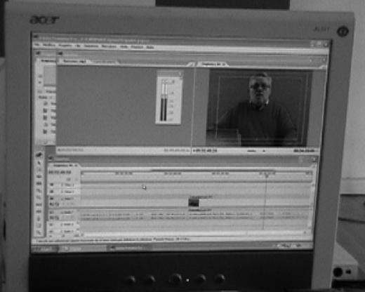 Computer monitor displaying video editing software with timeline, preview of a man speaking. CARID television,showing a TV segment in progress.