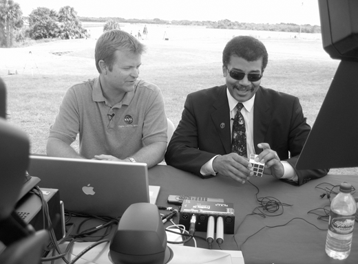 A black and white photo of Damon Talley (left) with Neil deGrasse Tyson (right), who is holding a Rubik's Cube.