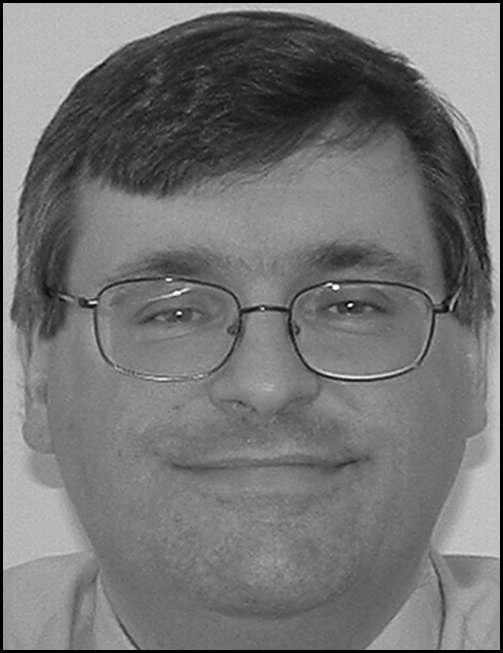 A portrait-style photograph of a man wearing glasses,named as Dean J. Tozzoli, listing a professional title, organization, street address, and telephone number.