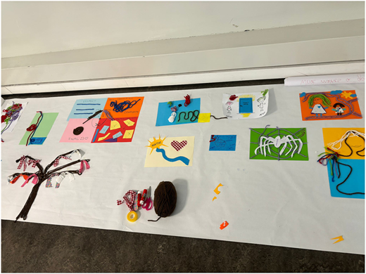 A photograph of handmade artwork on paper using wool, fabric, and stationery, arranged on a sheet.