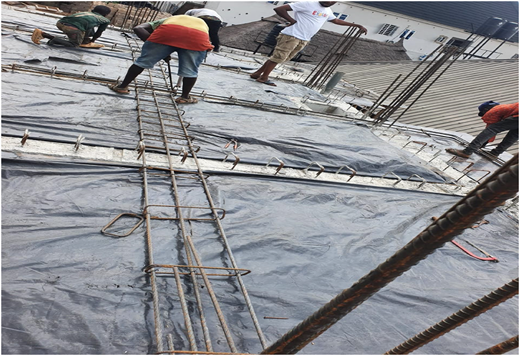 A photograph of workers tying steel reinforcements on a building slab without PPE, surrounded by rods and concrete framework.
