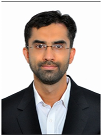 A photograph of Dr. Jawad Abbas, in glasses and formal attire, looking at the camera with a neutral expression.