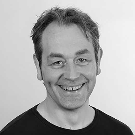 A portrait of an adult man with short hair, facing the camera and smiling.