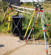 A surveying instrument mounted on tripods connected to a monitoring setup.