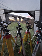 Multiple cameras on tripods arranged to monitor a railway bridge structure.