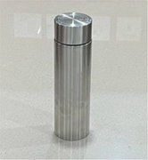 A stainless steel thermos with vertical grooves stands upright on a smooth surface.