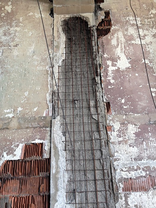 A wall reveals exposed concrete along with steel rebar, showing signs of damage and wear from previous repairs and weathering.