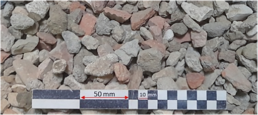 Gravel stones of irregular shape and varying sizes shown with a measuring scale indicating 50 millimeter and 10 millimeter divisions.