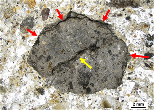 A close-up image of a rock surface with several arrows indicating cracks and features.