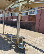 A metal bus shelter includes accessible seating and support rails positioned along a paved pedestrian walkway.