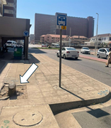 A damaged pavement beside a bus stop sign includes a broken concrete section highlighted with an arrow.
