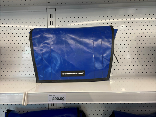 A DONNERSTAG messenger bag displayed on a perforated retail shelf with a price label reading 290.00 below the product.