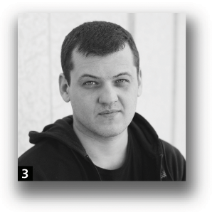 A man with short hair, wearing a hooded jacket over a dark shirt.
