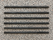 A set of six cylindrical rods arranged in parallel on a speckled surface.