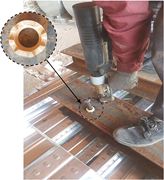 A worker uses a handheld installation tool on a steel plate, with an inset highlighting the circular fitting around the installed fastener.