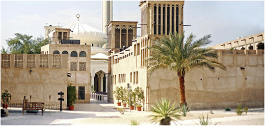 A photo shows a courtyard with traditional buildings, towers, a domed structure, and a palm tree.