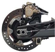 A motorcycle rear wheel brake assembly showing brake disc, caliper, mounting components, and surrounding mechanical structure.