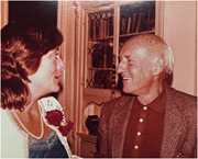 A woman and an older man conversing indoors.
