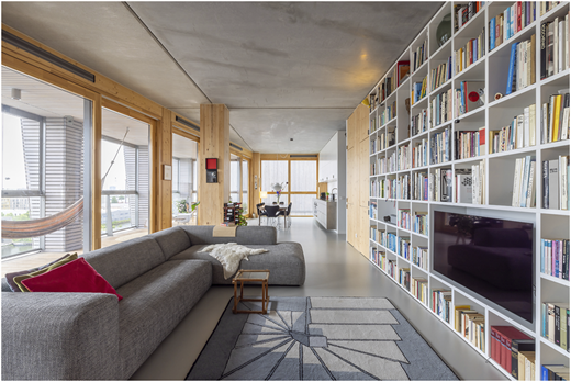 A photograph shows a modern open-plan living room with a gray sectional sofa, wall-length bookshelf, and dining area beyond.