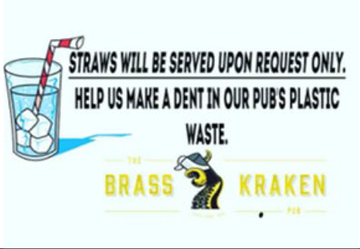 A sign at The Brass Kraken Pub advises that straws are available upon request only to reduce plastic waste, featuring an image of a drink with ice and a straw.