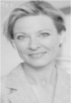 A black and white portrait photo of a smiling woman with short hair and a light colored blazer.
