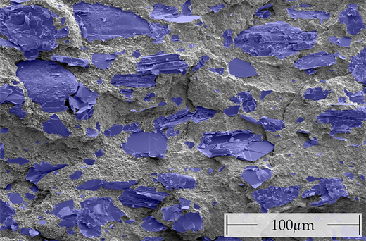 A microscopic image showing a textured surface filled with various shapes, depicting materials that display contrasting qualities of grey and blue tones.