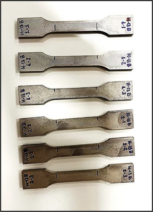 A set of 6 dog bone shaped tensile specimens has gauge marks, and handwritten H-13 B identifiers.