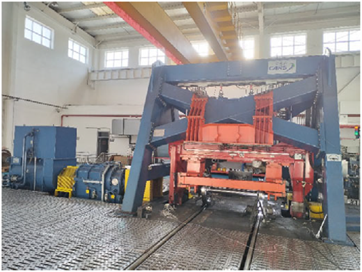 A photograph shows a large industrial test rig or machine inside a workshop.