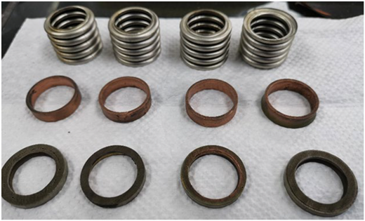Four metal springs and eight circular gaskets on a white surface.