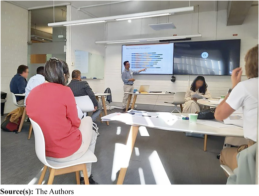 A group of people in a workshop setting, with one person presenting a slide.