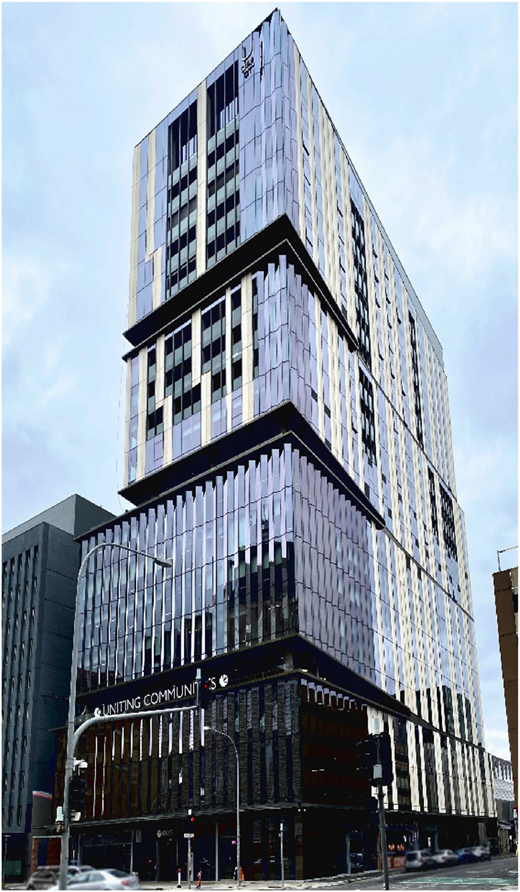 A photograph shows a modern multi-story building with a glass facade, showing a sleek and reflective exterior.