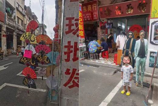 A street scene shows hanging decorative fans, storefronts with Chinese text, seated people outside a shop, cardboard cutout figures, and a child standing in the foreground.